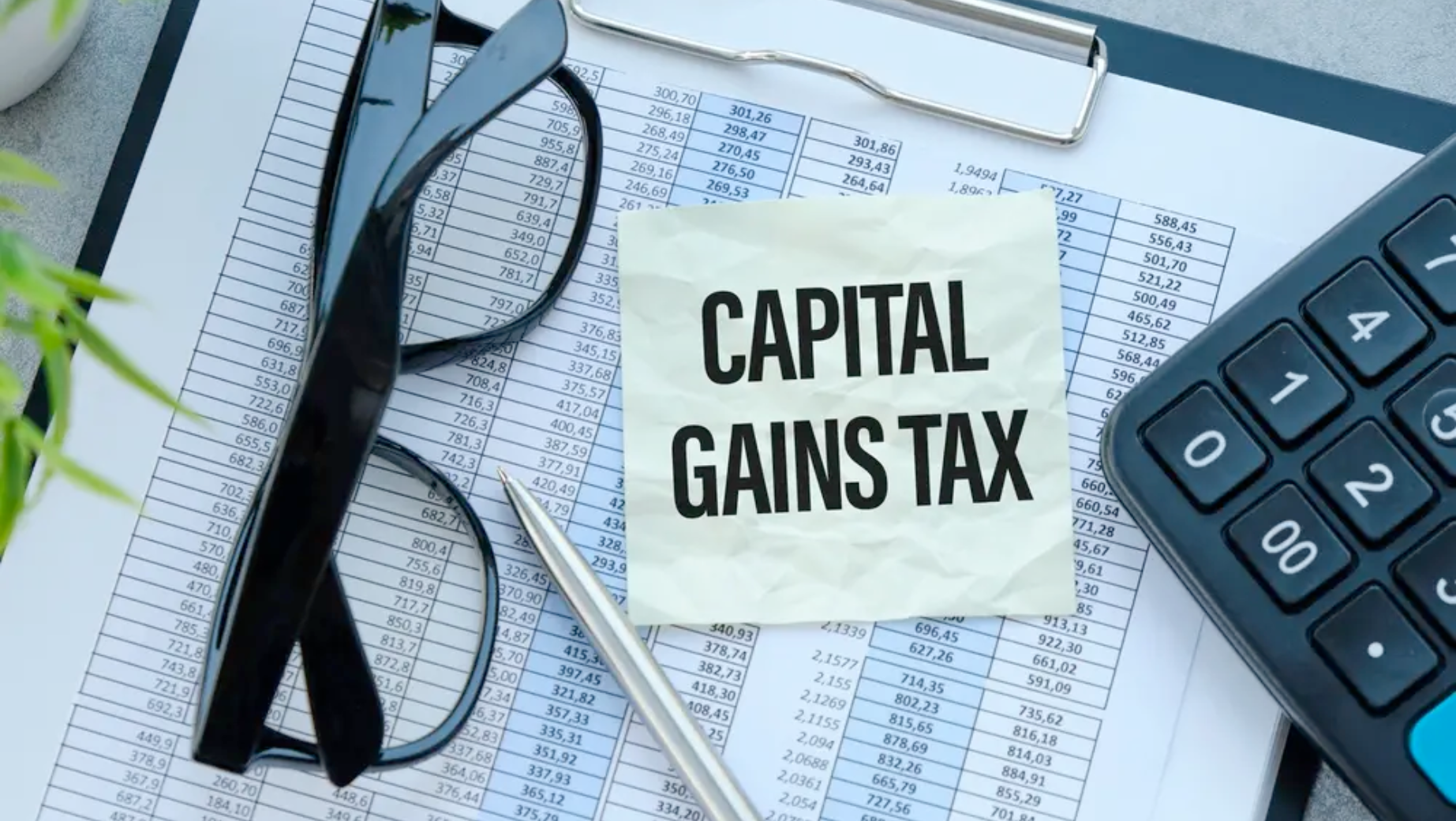 A pair of glasses, a pen, and a calculator lie on top of a financial document. A note with the text "CAPITAL GAINS TAX" is prominently placed on the document, highlighting the crucial work of business accountants in navigating these complex matters.