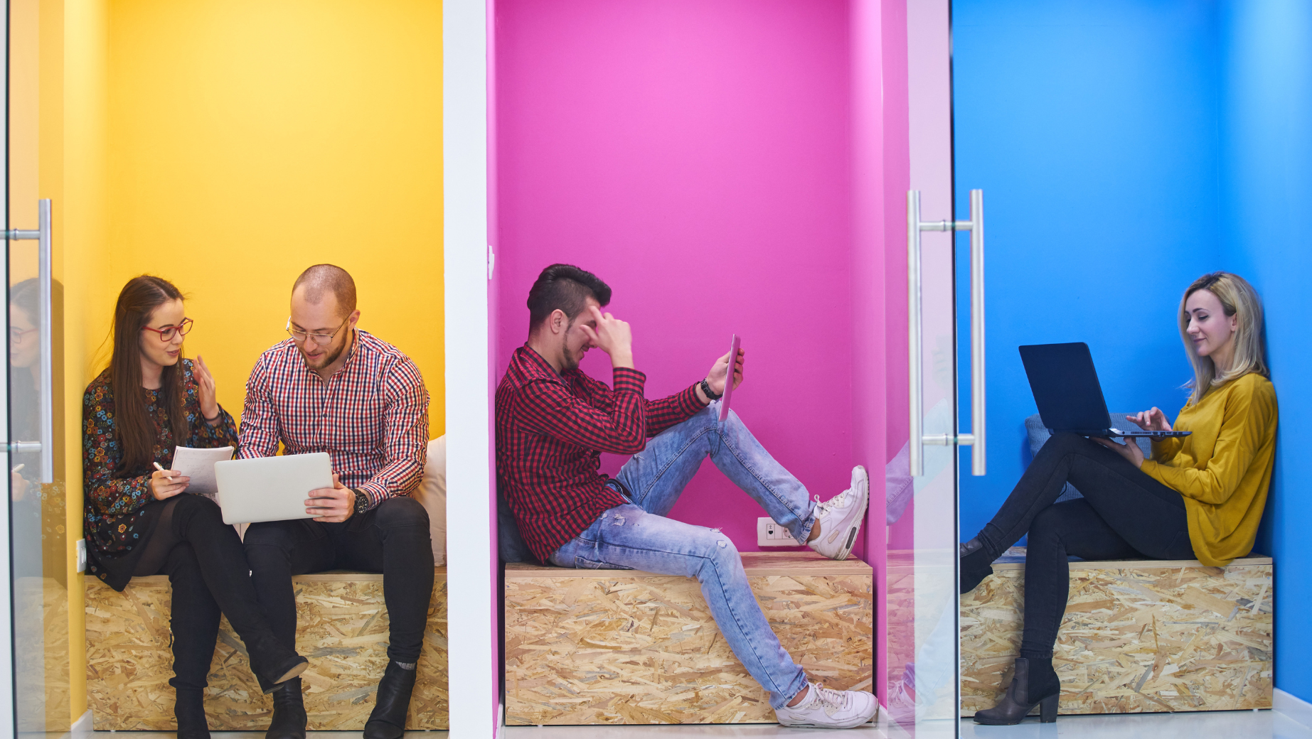 Three people are working in neighboring brightly colored cubicles. The first yellow cubicle hosts Business Advisors—a man and woman reviewing paperwork. In the second pink cubicle, an SMSF Accountant is using a smartphone. The third blue cubicle has a Tax Accountant working on a laptop.