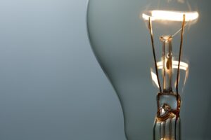 Close-up image of a glowing vintage-style incandescent light bulb, showcasing its filament inside a clear glass bulb against a minimalistic, light blue-gray background—perfectly illuminating the innovative ideas nurtured at Melbourne Accounting Firm.