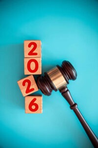 A judge's gavel rests beside wooden blocks stacked vertically, displaying the numbers 2026 in red on a blue background.
