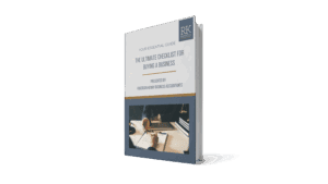 A 3D-rendered book titled "The Ultimate Checklist for Buying a Business" by Reid & Knotz Business Accountants, featuring a cover photo of hands writing on paperwork beside a laptop and coffee cup.