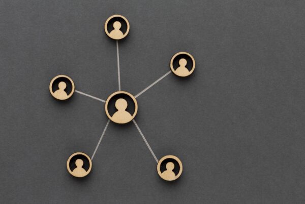 Wooden cutouts of five individuals are connected with strings, forming a network on a dark gray background. One central figure is linked to four surrounding figures, illustrating a hub-and-spoke model of connectivityโan apt metaphor for how our Melbourne Accounting Firm provides expert tax advice through your business accountants.